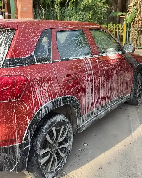 A red SUV covered in white foam outside a house